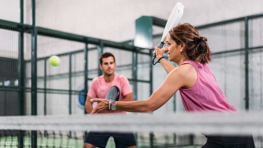 Recreatieve padelspelers tijdens een actieve en gezonde padelwedstrijd op een indoor padelbaan
