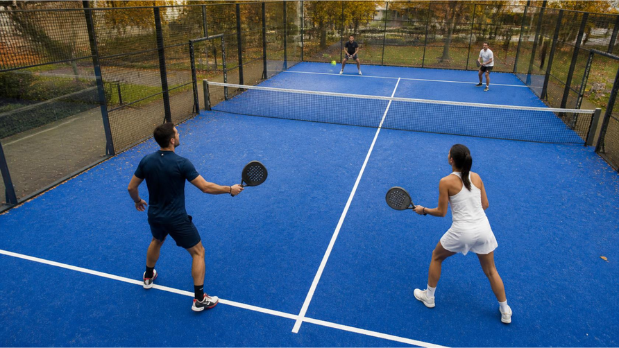 Twee dubbelpartners staan links en rechts op hun helft van de padelbaan