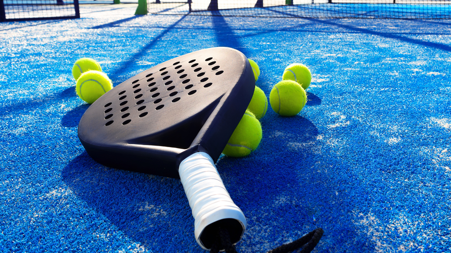 Padelracket met meerdere padelballen op een padelbaan