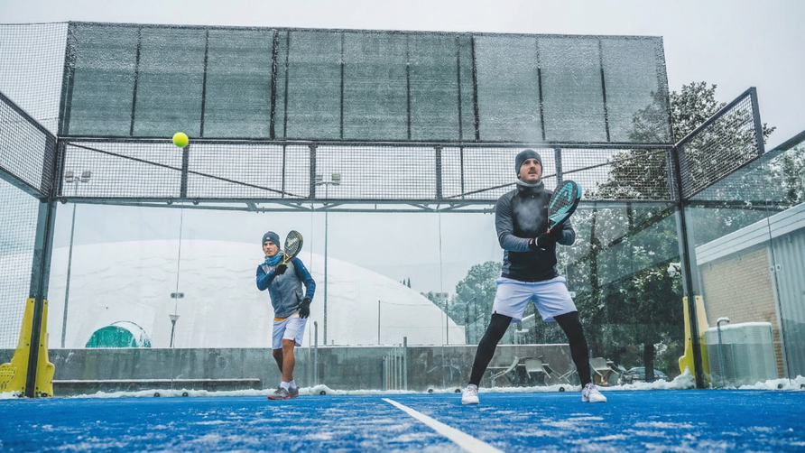 Padelspelers die in de winter op een koude, vochtige baan spelen